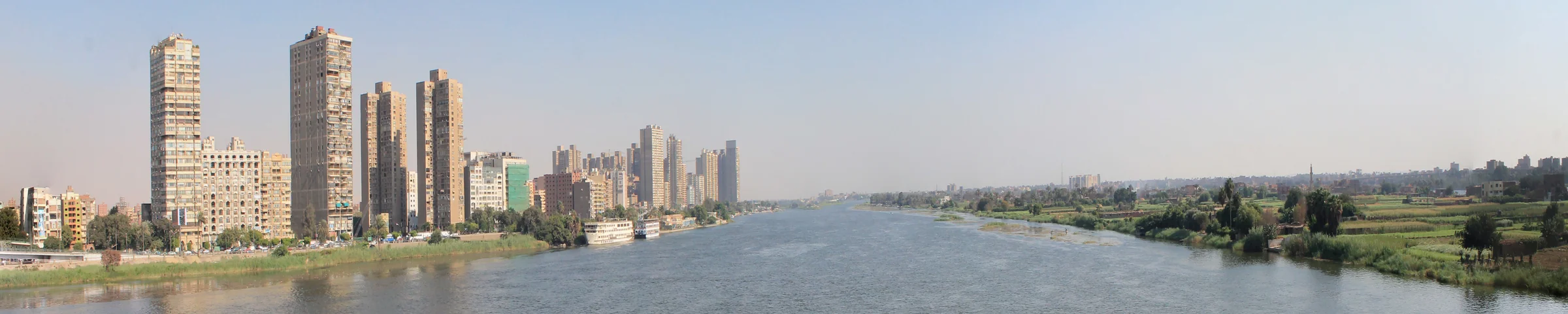 The Nile in Cairo between city buildings and a green riverbank