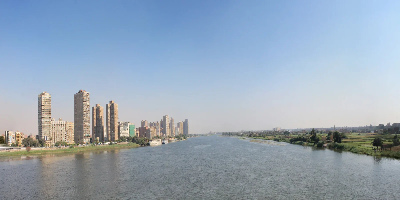 The Nile in Cairo between city buildings and a green riverbank