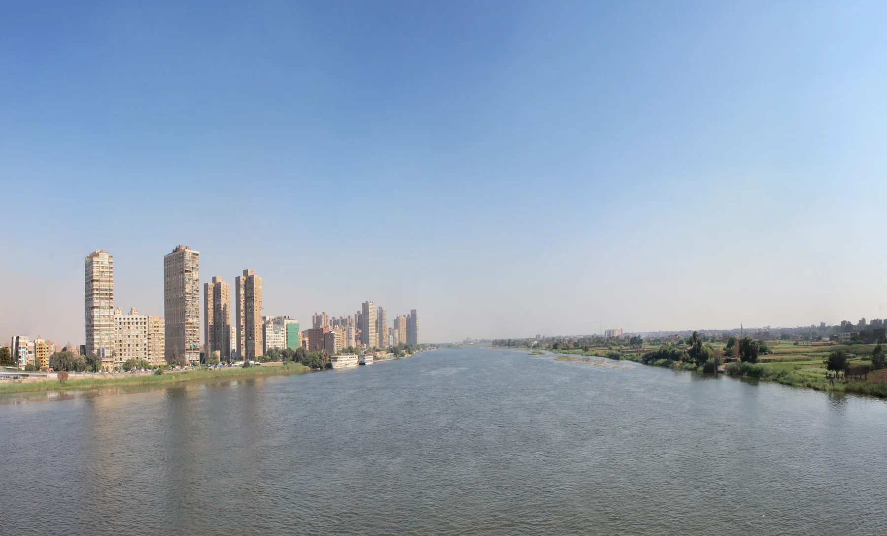 The Nile in Cairo between city buildings and a green riverbank
